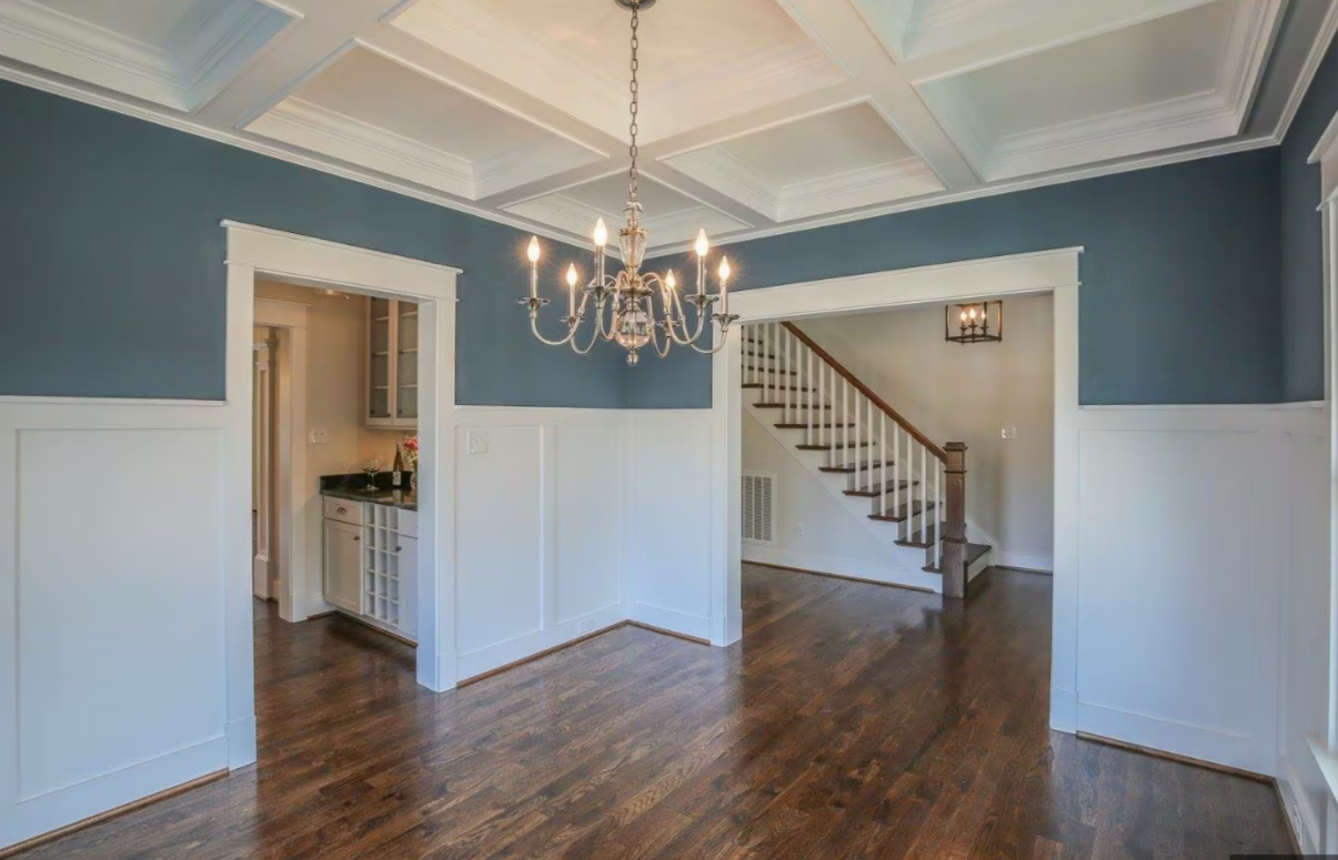 Finished dark hardwood floor with custom white trim and staircase